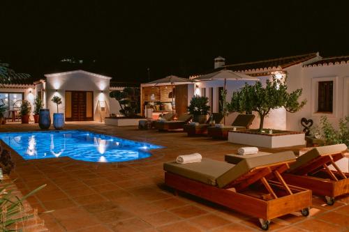 una piscina en un patio con sillas y una casa en San Roque Suites de Monda, en Monda