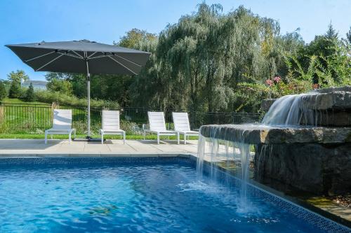 einen Pool mit einem Sonnenschirm und Stühlen sowie einem Brunnen in der Unterkunft Bromont Lodge 871 Shefford suite 205 in Bromont