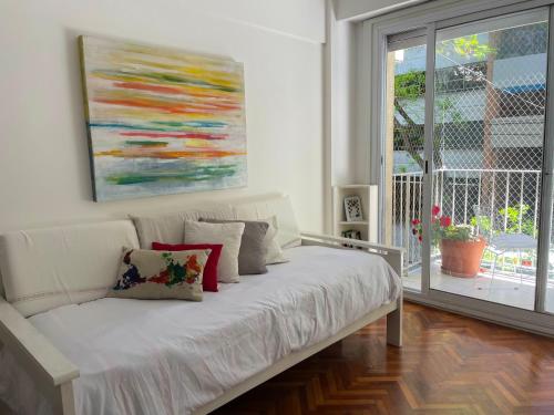 Una cama blanca en una habitación con un cuadro en la pared en Studio Palermo Hermoso Con Balcon en Buenos Aires