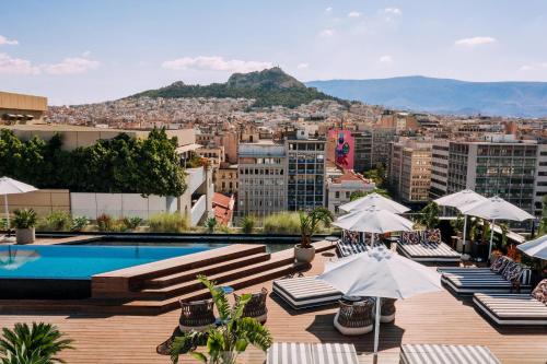 uma piscina no último piso com cadeiras e guarda-sóis e uma cidade em Skylark, Aluma Hotels & Resorts em Atenas