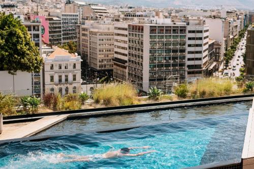 a person swimming in a swimming pool on top of a building at Skylark, Aluma Hotels & Resorts in Athens