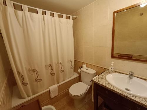 a bathroom with a shower curtain and a toilet and a sink at Inmocyma Cerler-Prados de Velarta C2 8 -vistas panorámicas in Cerler