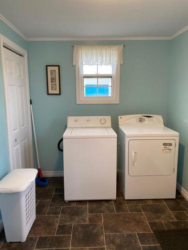 a laundry room with a washer and dryer and a window at Storytellers Retreat in Twillingate