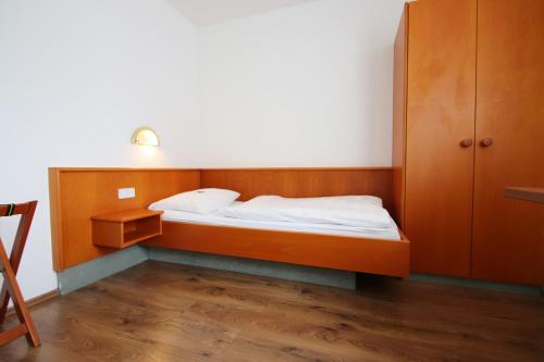 a small bedroom with a bed and a cabinet at Hotel-Dörfler Garni in Kahl am Main