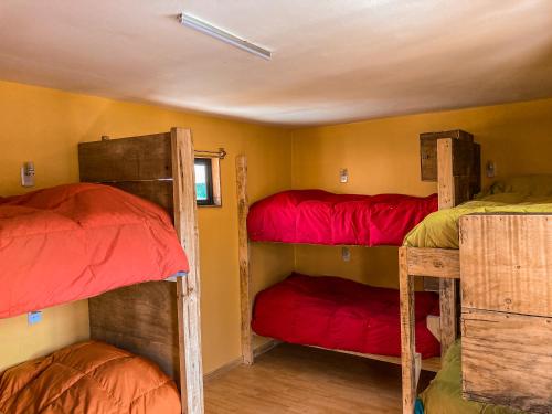 a room with three bunk beds with red sheets at Willhouse Hostel in Pucón