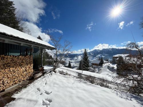 un patio cubierto de nieve junto a una casa con el sol en Bregenzerwald Ferienhaus, en Egg