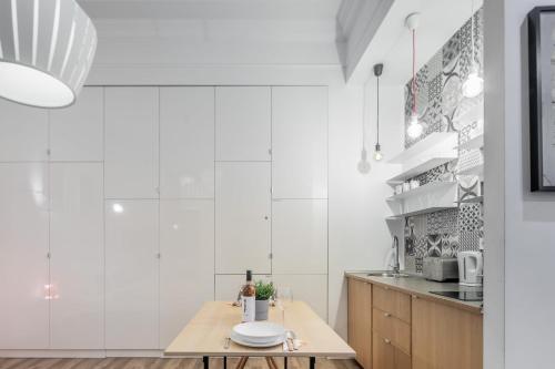 Extra Central Modern Studio في بودابست: مطبخ بجدران بيضاء وطاولة خشبية