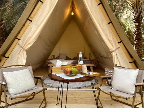 Husaak Glamping في العلا: طاولة مع وعاء من الفواكه في خيمة