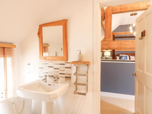 a bathroom with a sink and a mirror at Dovecote Cottage in Ashbourne