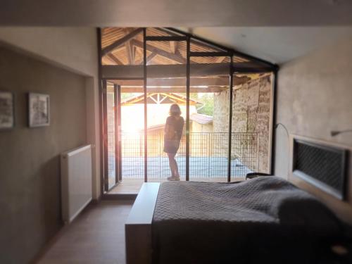 a woman standing outside of a bedroom with a bed at La ferme de Berlioz in La Côte-Saint-André