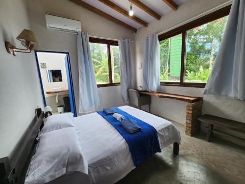 Schlafzimmer mit einem Bett, einem Spiegel und Fenstern in der Unterkunft Bangalô com Vista Parcial para o Mar in São Sebastião