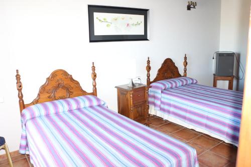 two beds with striped sheets in a room at Hostal Rural Turre in Turre