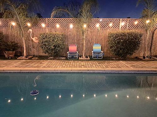 two chairs sitting next to a swimming pool at night at Tropical Paradise in Fresno