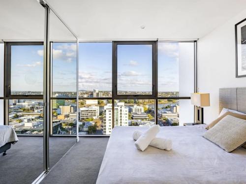 布里斯班Riverview 2BR delicate Apt, 1min to train station的卧室里有一张白色的大床和大窗户