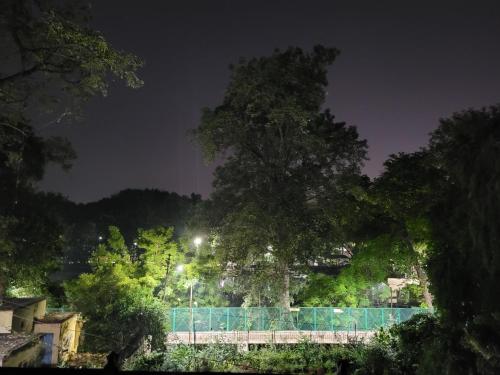 a tennis court with a fence and trees at night at Hotel Ananda Kashi in Varanasi