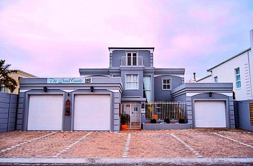 a house with three garage doors in front of it at The Sandcastle Guesthouse - Melkbosstrand in Melkbosstrand