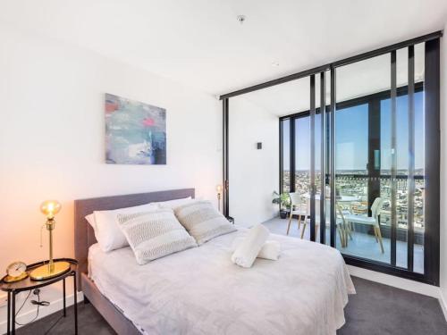a bedroom with a large white bed and a balcony at Story Bridge and City View Skyhigh Luxe 2 bed Unit in Brisbane