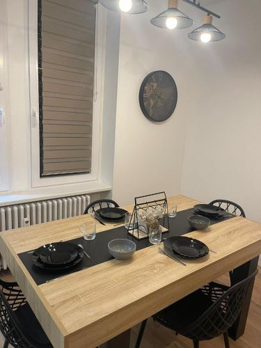 une table en bois avec des chaises et une horloge sur le mur dans l'établissement Appart 3p RDC Orangerie- Parlement européen, à Strasbourg