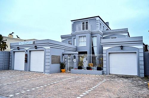 a large white house with two garages at The Sandcastle Guesthouse - Melkbosstrand in Melkbosstrand