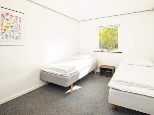 Cette chambre blanche dispose de deux lits et d'une fenêtre. dans l'établissement Holiday home Læsø, à Læsø