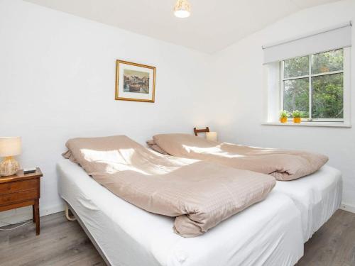 two beds in a white room with a window at Holiday home Læsø IV in Læsø