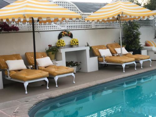 een zwembad met stoelen en een parasol naast een zwembad bij Our Hermanus House in Hermanus
