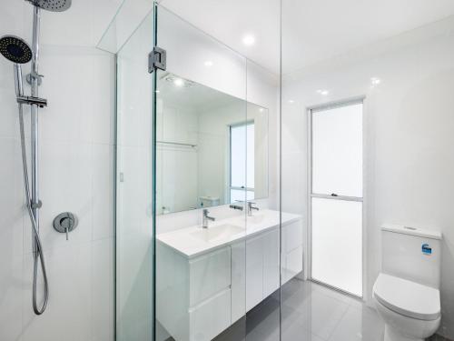 a white bathroom with a sink and a toilet at 4BR Cozy house 5mins to beach in Gold Coast