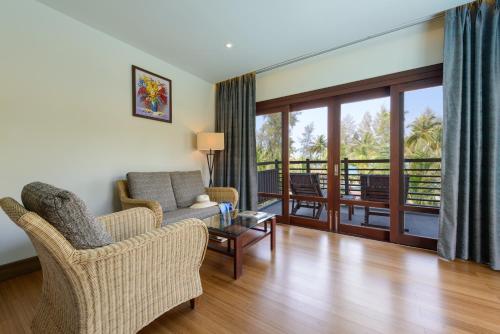 a living room with a couch and chairs and a balcony at The Haven Khao Lak in Khao Lak