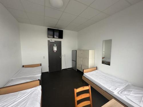 ein Zimmer mit 2 Betten und einem Stuhl darin in der Unterkunft Arena Hostel & Monteurzimmer in Hamburg