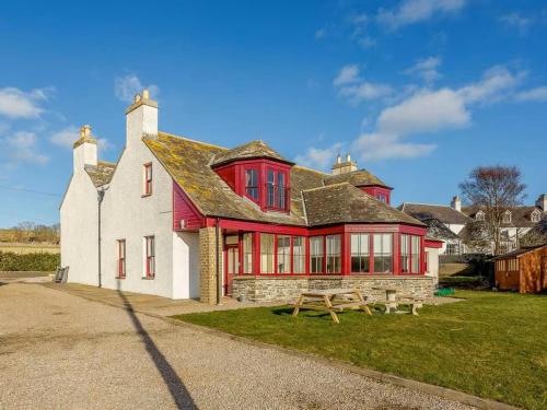 a red and white house with a picnic table in front of it at Craiglea Lodge in Latheron