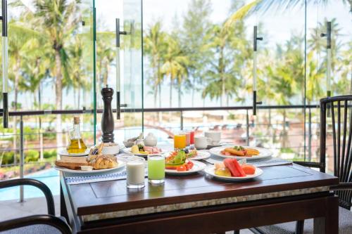 a table with plates of food and drinks on it at The Haven Khao Lak in Khao Lak