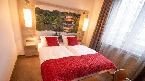 Schlafzimmer mit einem Bett mit einer roten und weißen Decke in der Unterkunft Hotel Hellers Krug in Holzminden