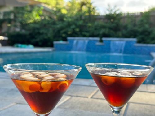 two cocktails sitting on a table next to a pool at 4 Bedroom Clearwater Vacation Home with Amazing Backyard in Clearwater