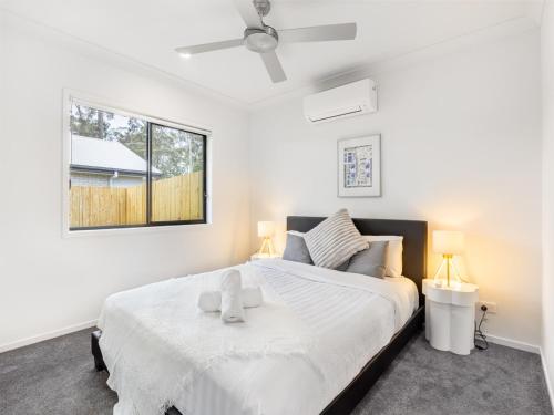 a bedroom with a large white bed with two lamps at Brand New 2BR well designed home at Brown Plains in Browns Plains