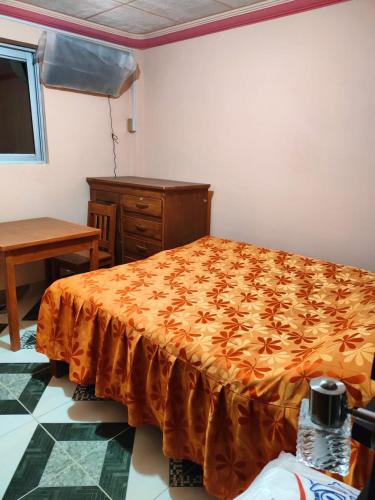a bedroom with a bed and a dresser and a table at Hostal Puesta de Sol in Uyuni