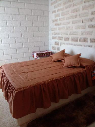 a bed in a room with a brick wall at Hostal Puesta de Sol in Uyuni