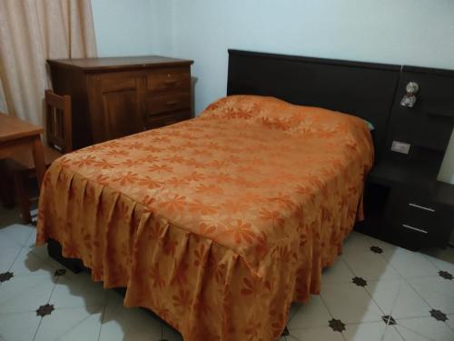 a bedroom with a bed with an orange blanket on it at Hostal Puesta de Sol in Uyuni