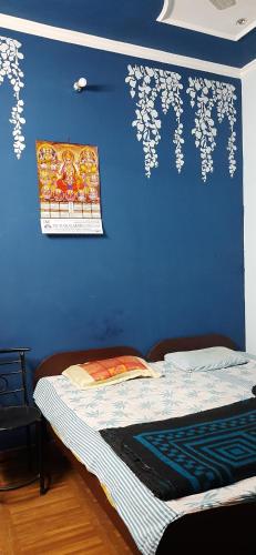 a blue wall with a bed in a room at Balaji Guest House - Home Stay in Greater Noida
