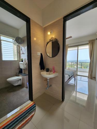 a bathroom with a sink and a mirror and a bed at Trinity Stays Nashik - Mountain view apartment close to Sula in Nashik