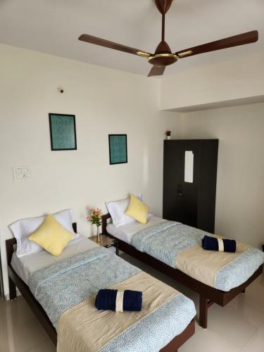 two beds in a room with a ceiling fan at Trinity Stays Nashik - Mountain view apartment close to Sula in Nashik