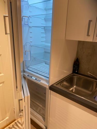 einem leeren Kühlschrank mit offener Tür neben einem Waschbecken in der Unterkunft Sentral 4-roms leilighet i Trollbakken in Tromsø