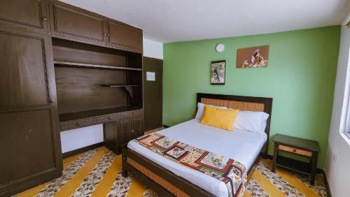 um pequeno quarto com uma cama e paredes verdes em Tuki Hostel & Lounge em Pereira