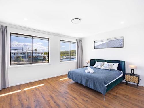 a bedroom with a bed and two windows at Stunning waterfront family home with pontoon newly in Gold Coast