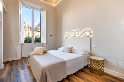 a white bedroom with a bed and a window at Vittoria Luxury House in Lecce