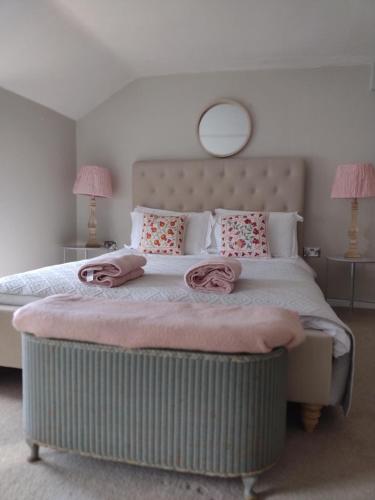 a bedroom with a large bed with pink towels on it at Samphire Cottage in Helston