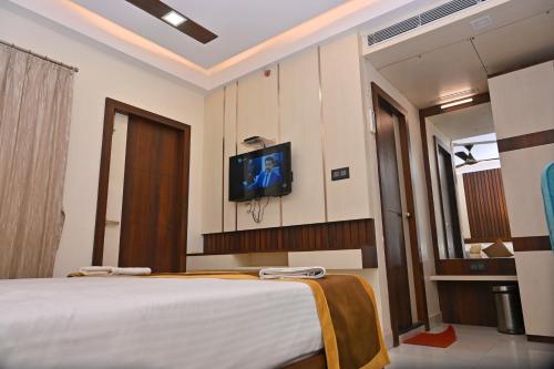 a bedroom with a bed and a tv on the wall at Hotel Silver Land New Digha with Rooftop Pool in Digha