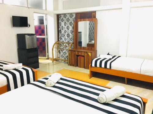 a hotel room with two beds and a television at Aura City Hostel in Anuradhapura