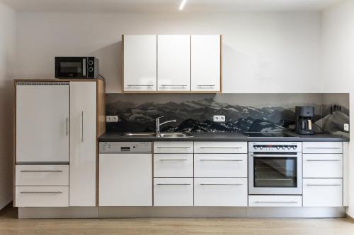 a kitchen with white cabinets and a sink at Appartement Monika in Neukirchen am Großvenediger