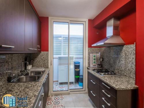 uma cozinha com paredes vermelhas, um lavatório e um fogão em Casa Ànima em Platja d'Aro