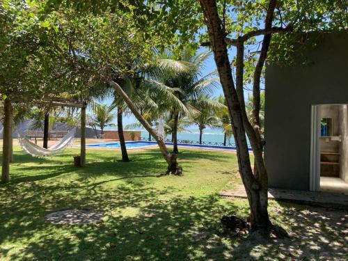 a park with a hammock and trees and the beach at Villa Patara in Marechal Deodoro